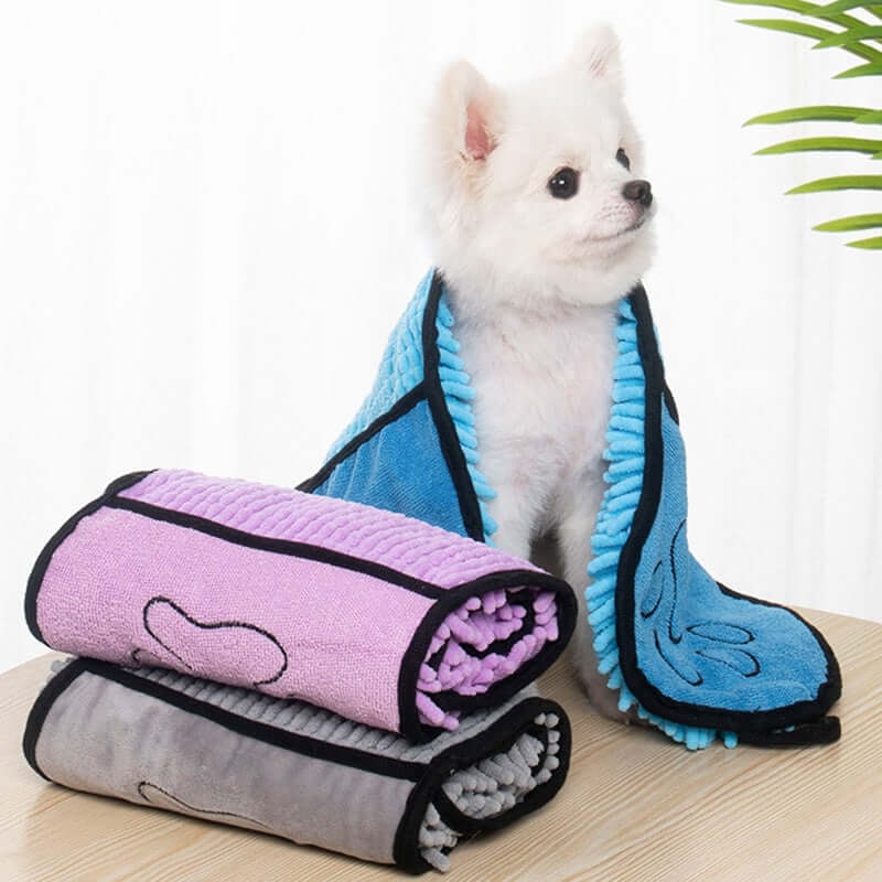 Premium pet supplies including a cozy pet towel and a small dog wrapped in a colorful drying towel.