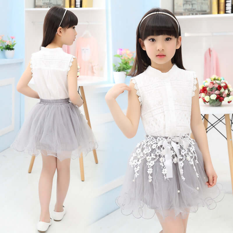 Cute girl wearing a fashion lace dress with a sleeveless white top and grey tulle skirt.