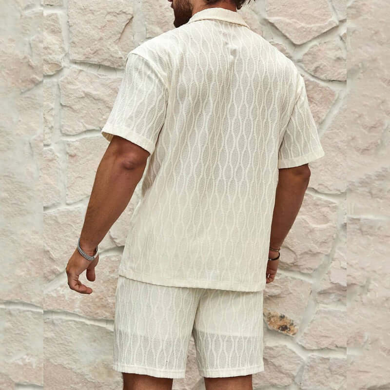 Men's summer tracksuits showcasing a stylish milky white short-sleeve top and shorts against a textured stone wall.