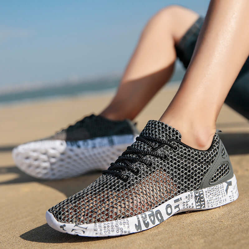 men's breathable sneakers on a beach, showcasing lightweight mesh design and casual sporty style.