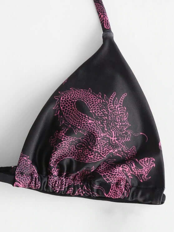 Close-up of a sexy printed bikini featuring a dragon design in pink on a black background.