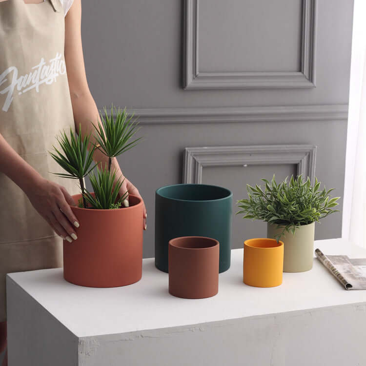 Nordic ceramic flowerpot with drainage hole displayed in various sizes with plants on a table.