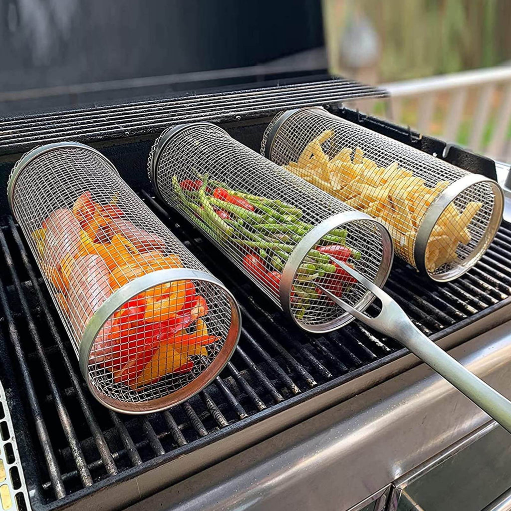 Stainless steel grill basket with vegetables and peppers on a BBQ grill for even cooking.