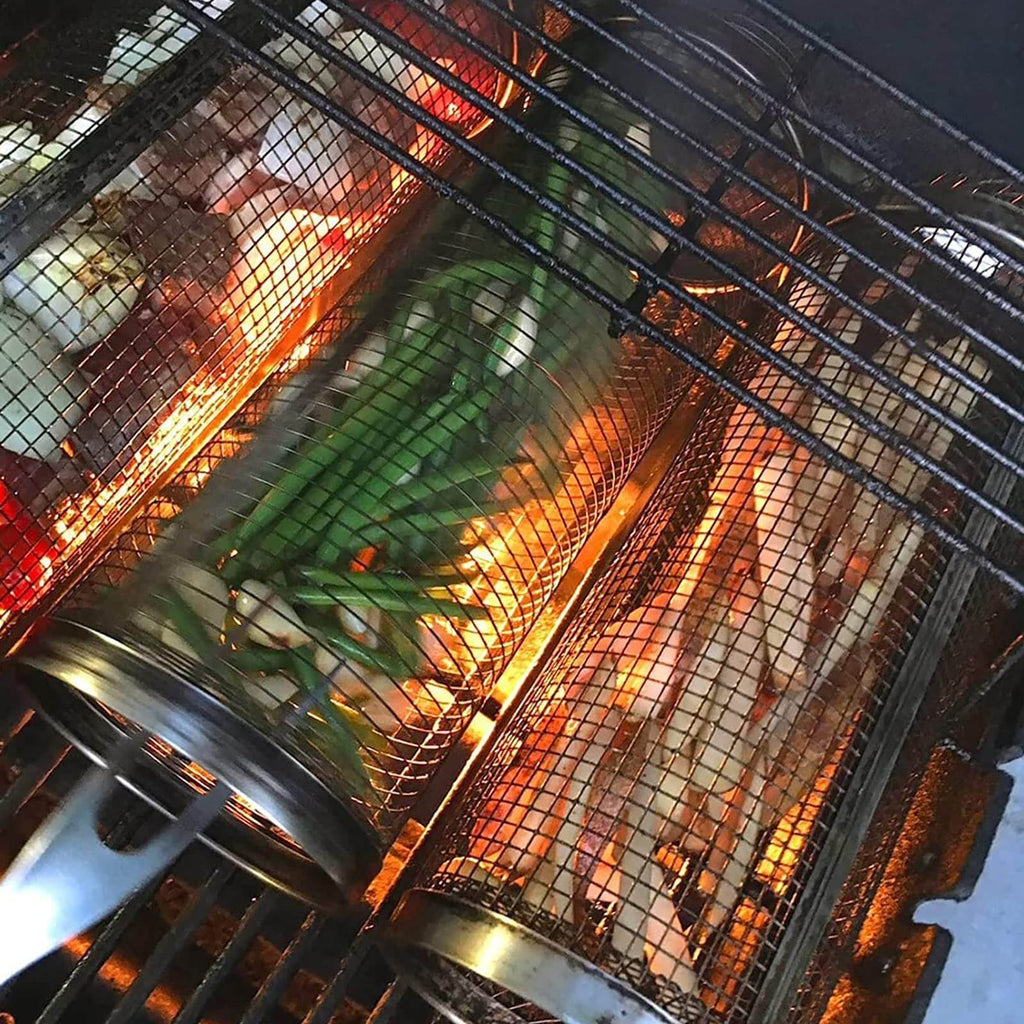 Stainless steel grill basket with vegetables cooking on a BBQ grill, featuring a cylindrical rotisserie design.