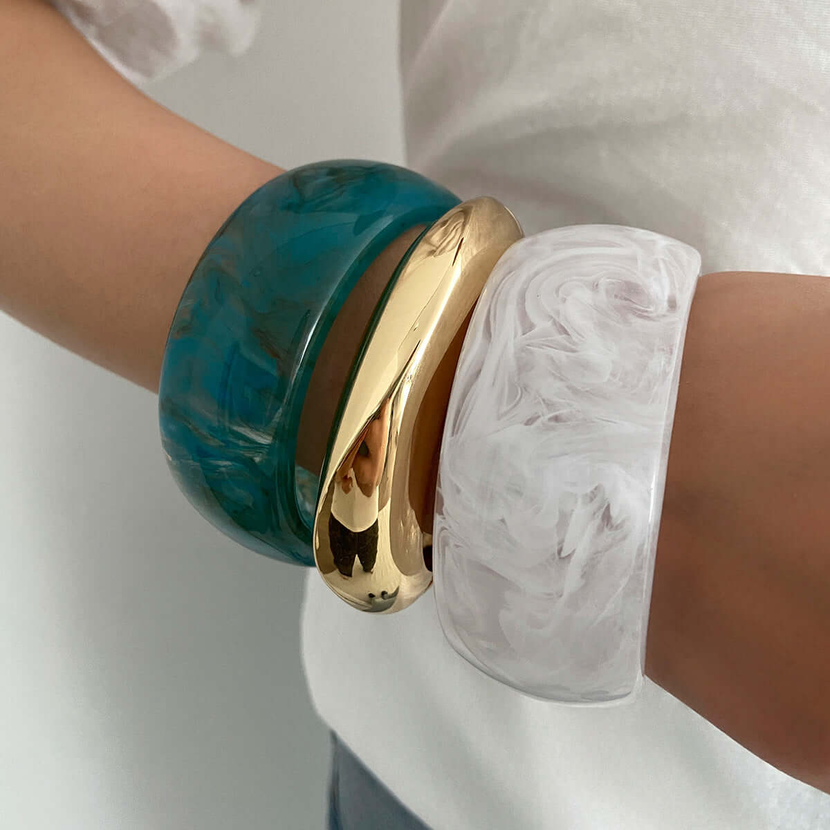 Handcrafted resin-dyed bracelet in vibrant colors, showcasing unique patterns on a wrist with other bangles.