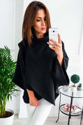 Woman in black comfortable everyday sweatshirt posing with a phone in a bright room, surrounded by plants.