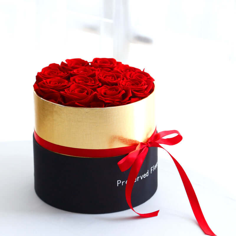 Preserved real roses gift box with red roses, presented in a luxury black and gold box, tied with a red ribbon.