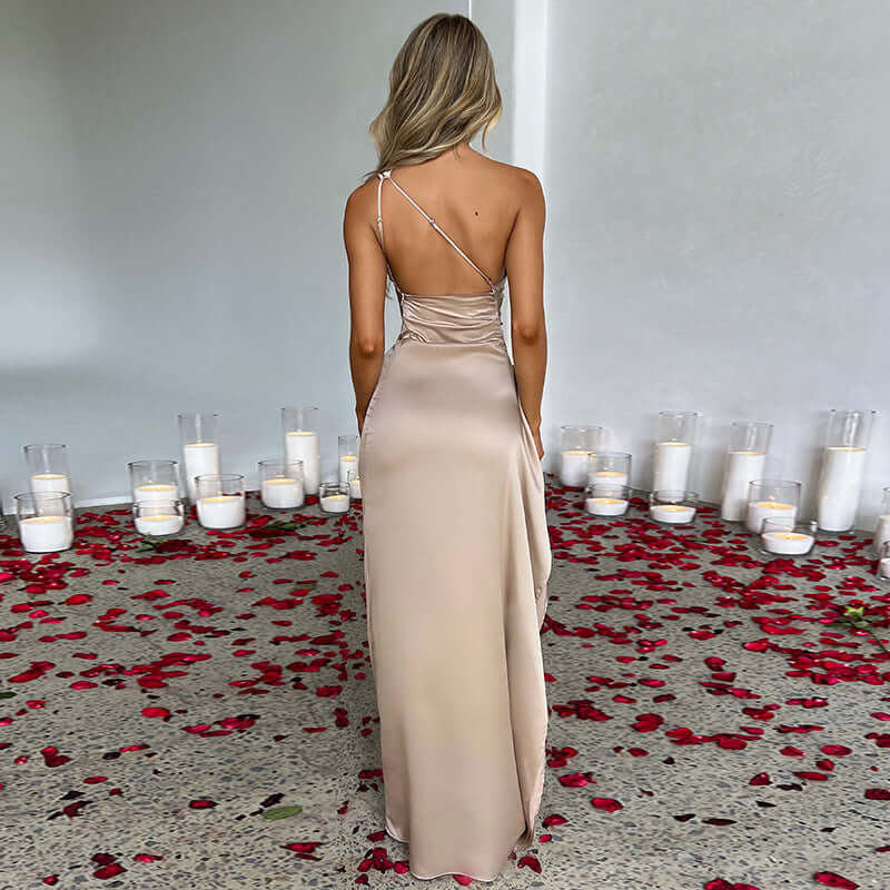 Back view of a woman in a backless slit evening gown on a bed of rose petals with candles.