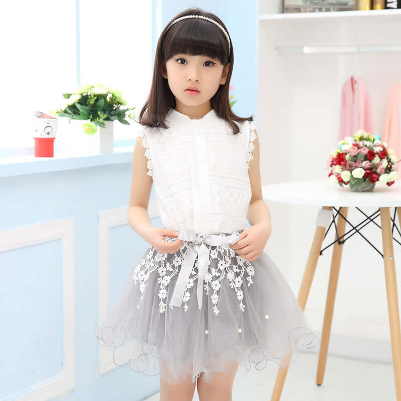 Fashion lace dress on a young girl, featuring a sleeveless white top and a grey lace skirt with floral patterns.