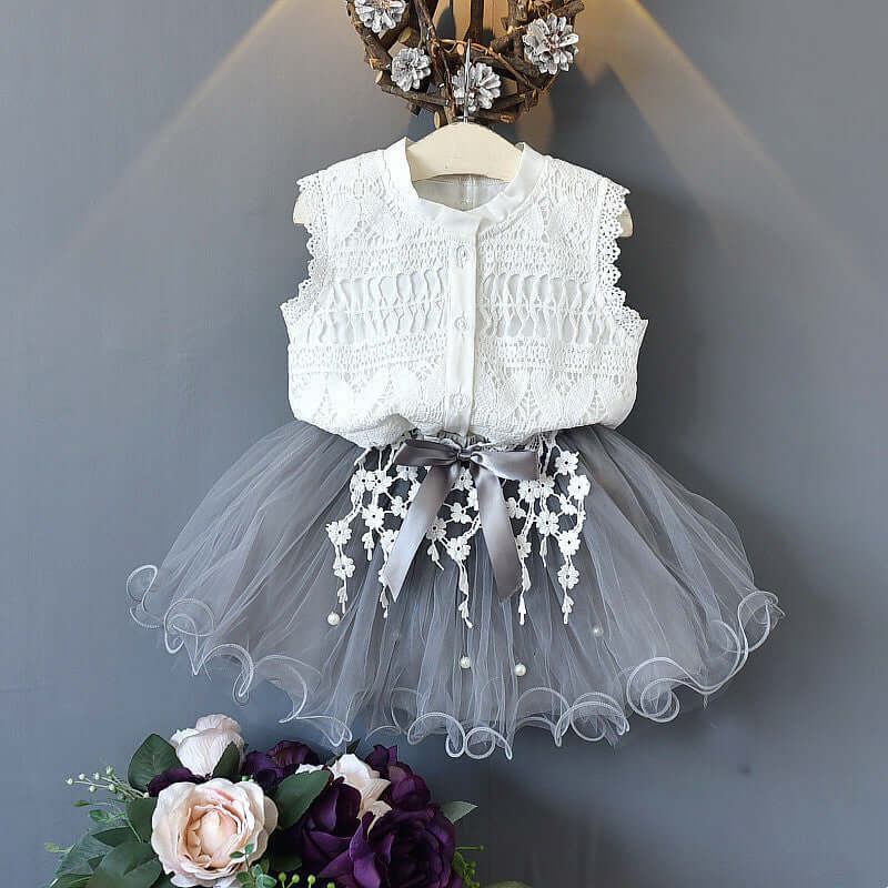 Fashion lace dress featuring a sleeveless white lace top and a grey tulle skirt with floral details and a bow.