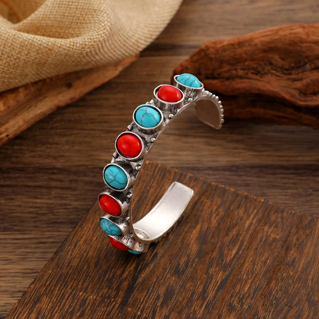 Ring-shaped electroplated bracelet featuring red and blue stones against a silver base.