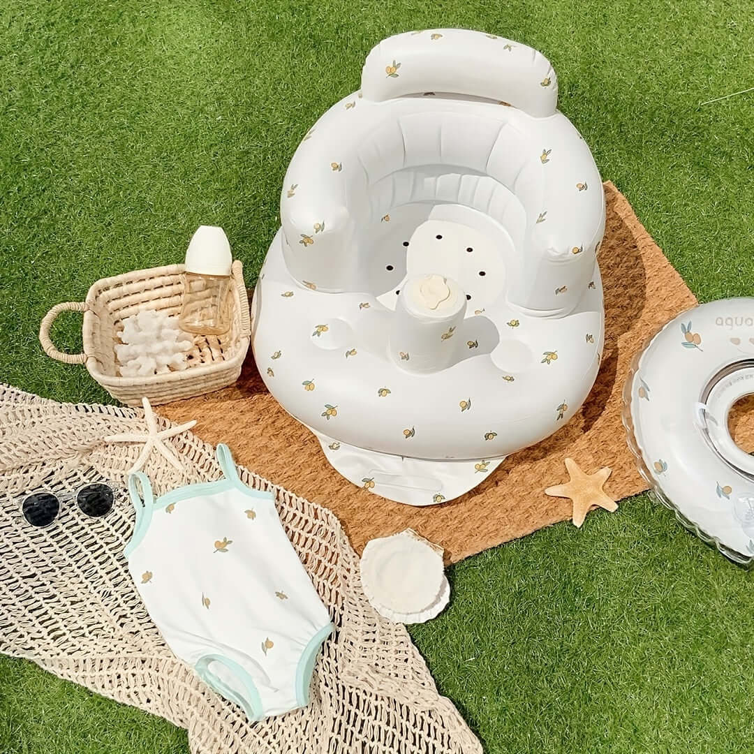 The Ultimate Learning Chair For Babies displayed on grass with a swimsuit and beach accessories.